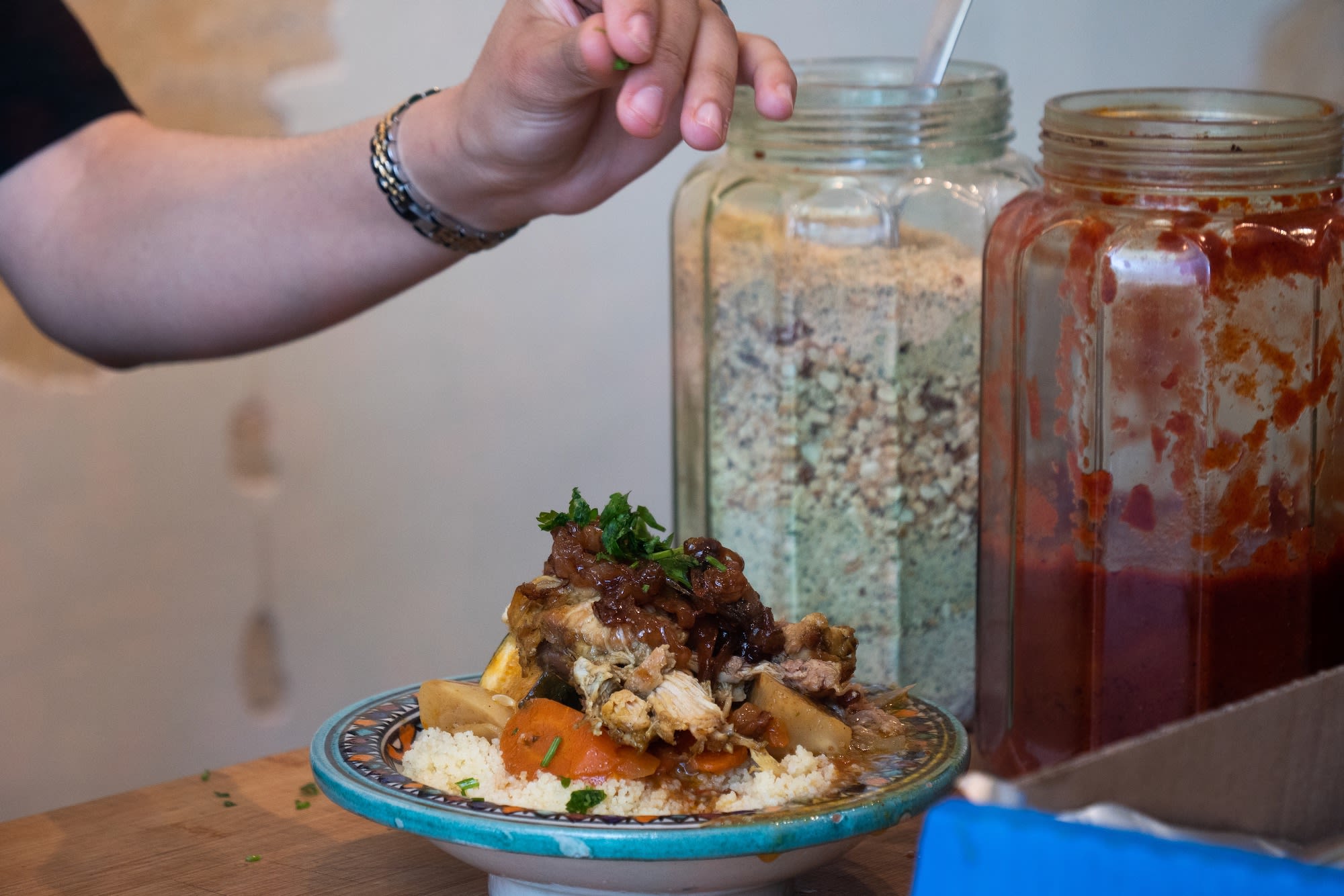 Woman's hand decorating an elaborate traditional Moroccan dish at Amsterdam restaurant Couscous Bar