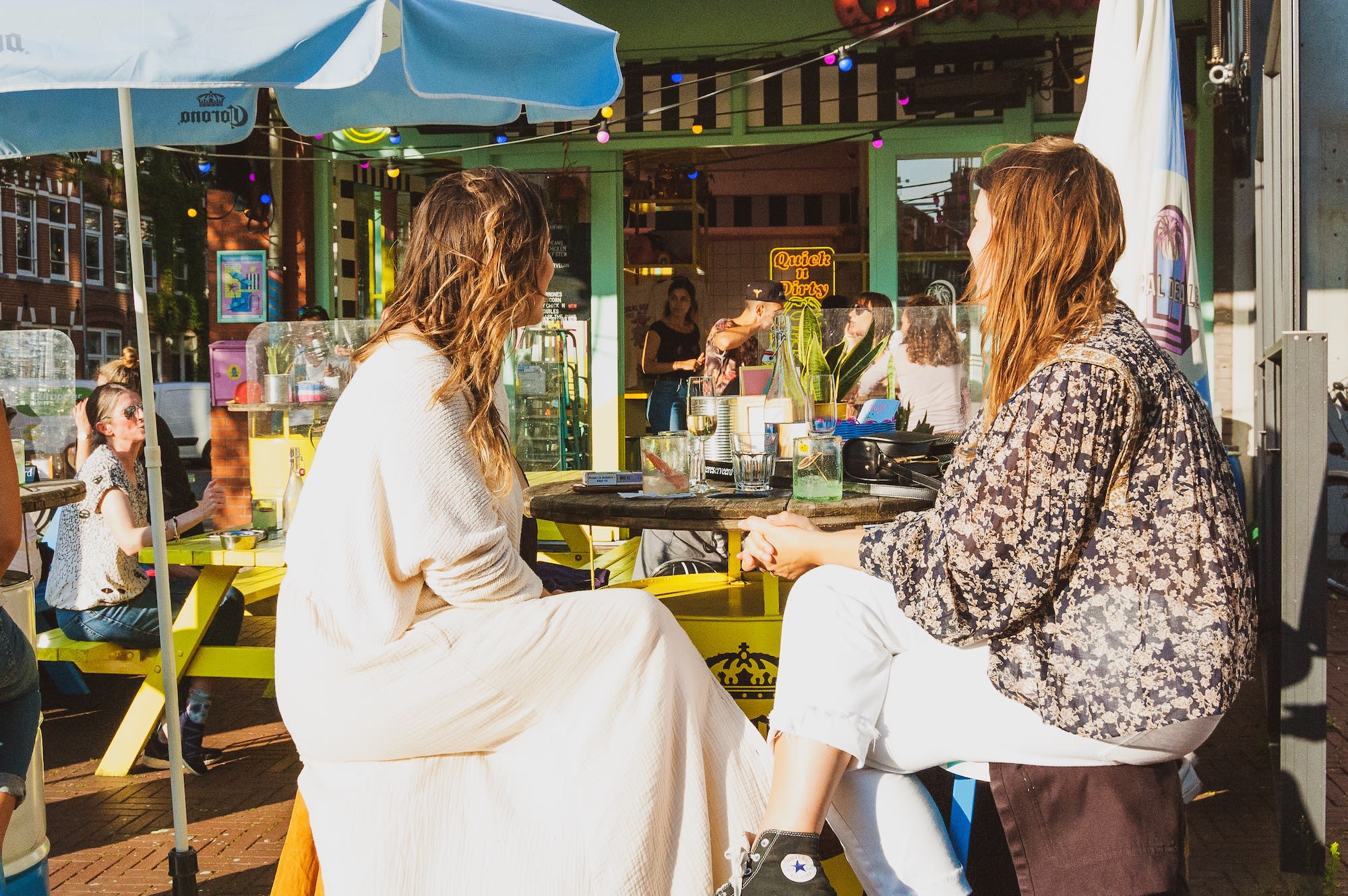 Sunny Amsterdam terrace of funky Mexican restaurant Local Dealer with two women enjoying their meal under an umbrella