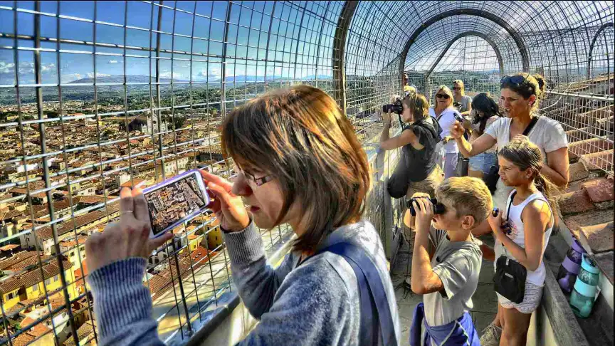 Tourists taking photos from a caged lookout over a European city