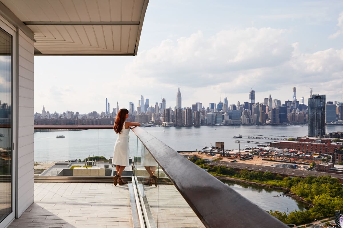 Corner Suite With Wraparound Balcony, woman enjoying the city view from the balcony Image