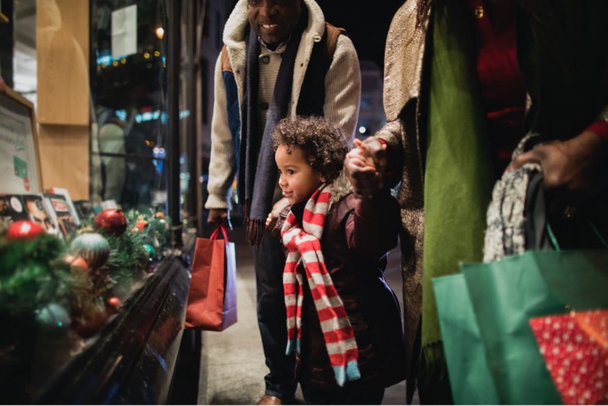 papa noel kid with grandparents outside store window
