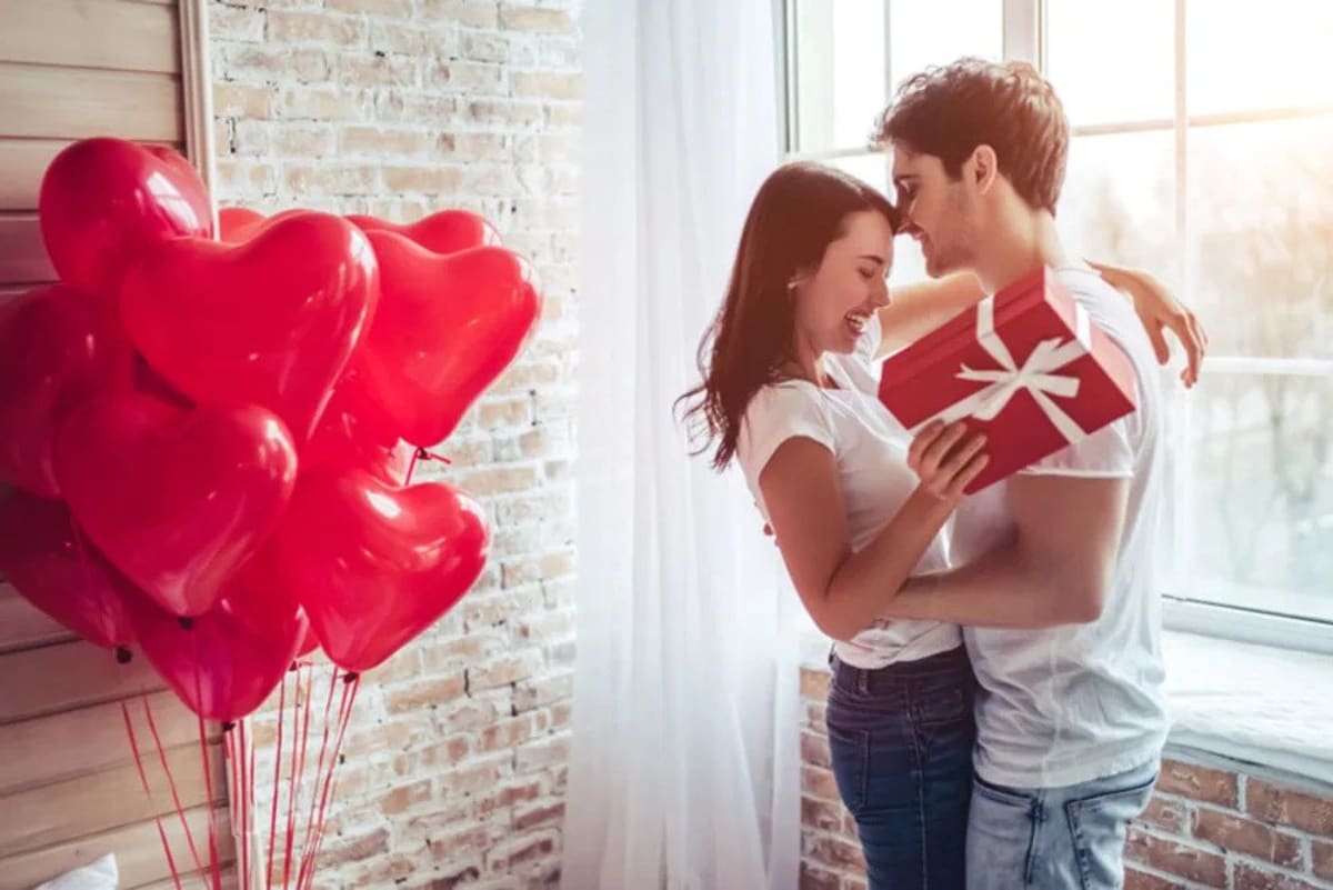 Young couple hugging, laughing and exchanging Valentine's Day presents.