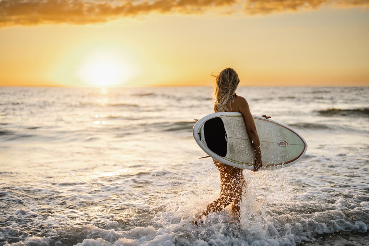 A women running into the sea with a surf board