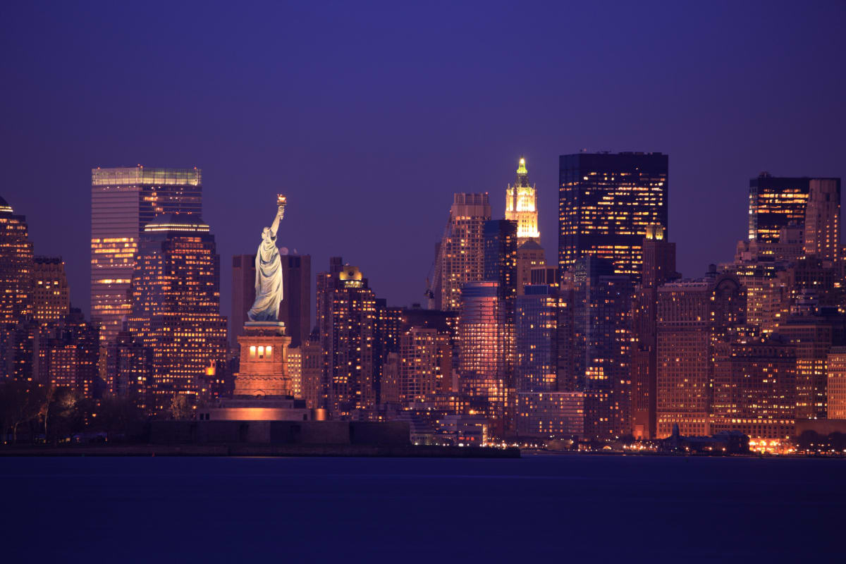 New York skyline at night with statue of liberty in front