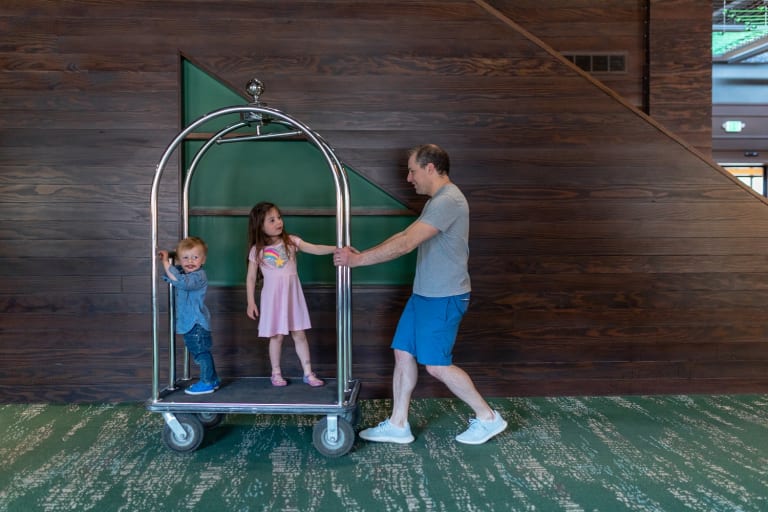 dad pushing two kids on bell cart