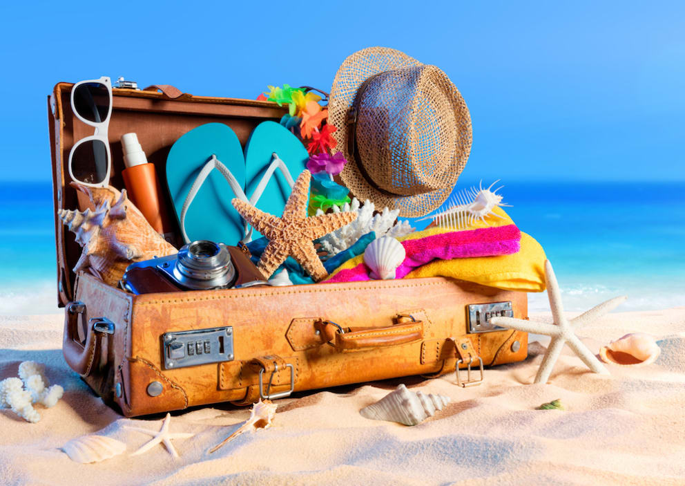 suitcase with beach essentials on beach