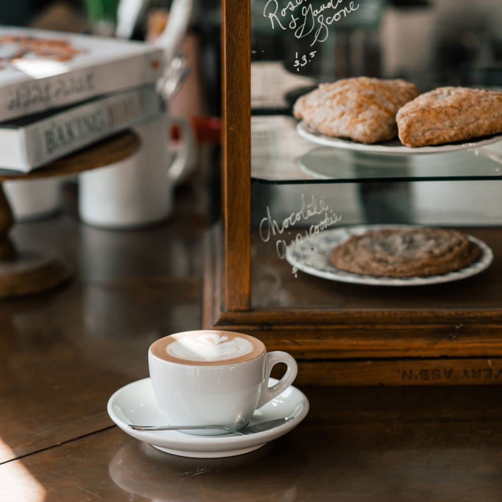 A cup of coffee in front of a pastry case