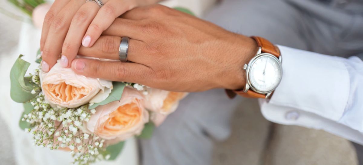 Weddings, closeup of couple placing hands on bouquet