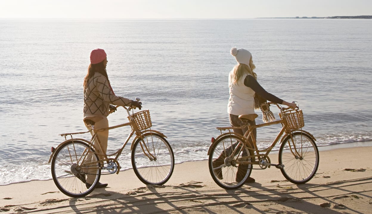 Women standing by bikes by the sea