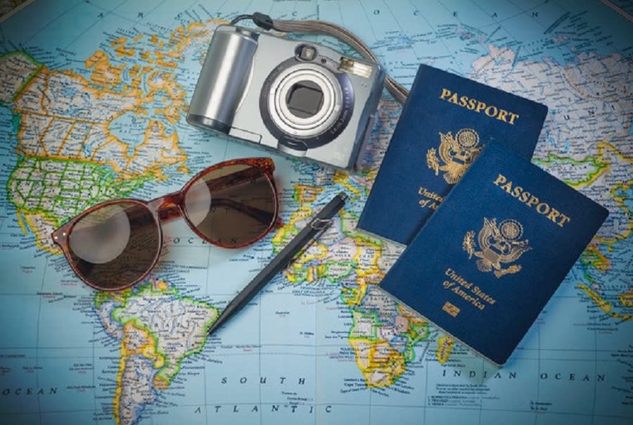 pen, passport, camera and sunglasses placed on a world map