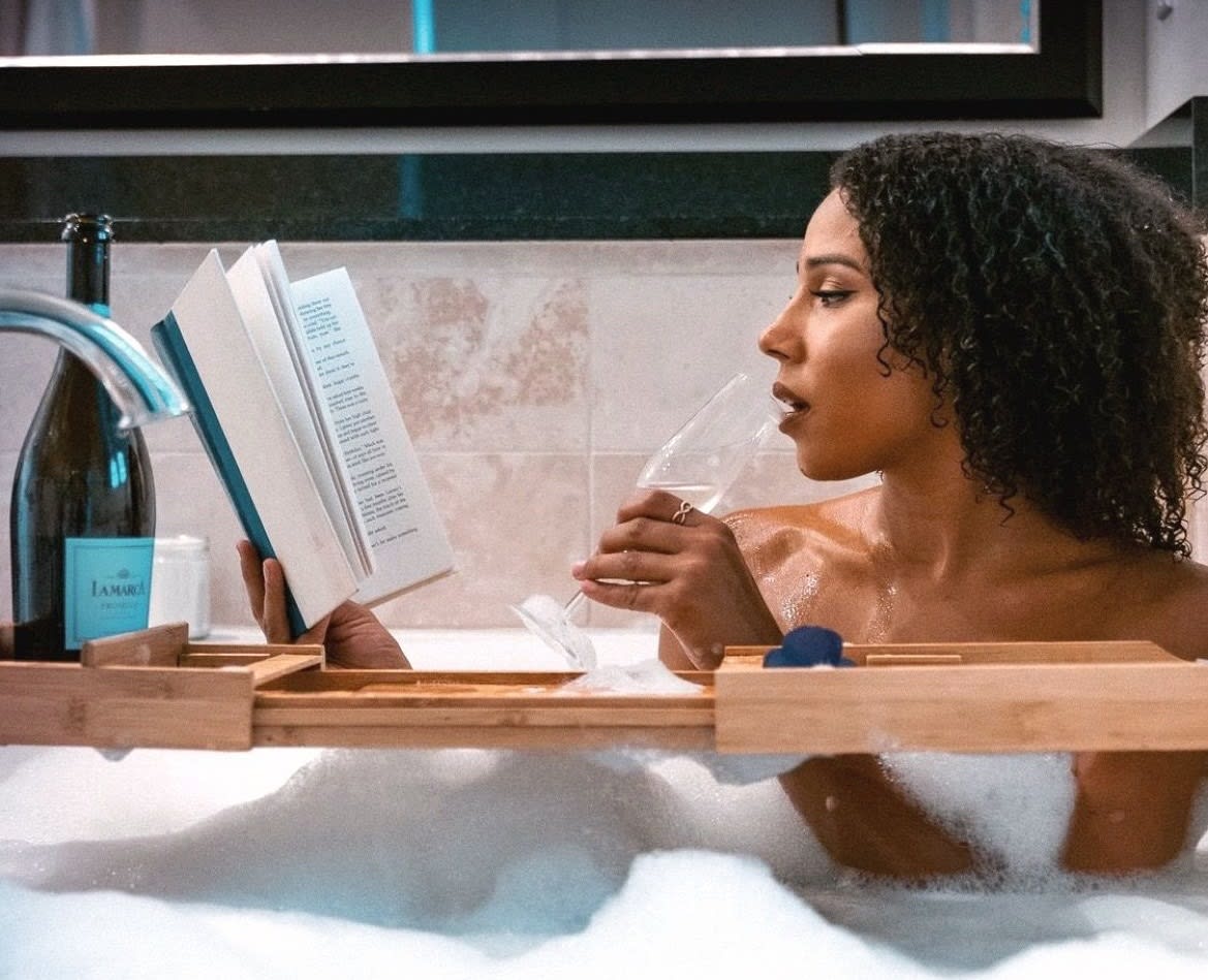 Woman in bubble bath drinking champagne and reading a book