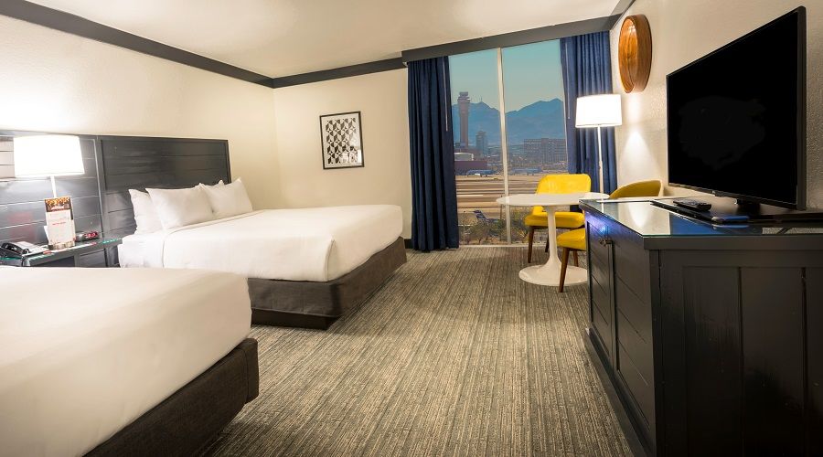 Two queen bed next to window with airport view.