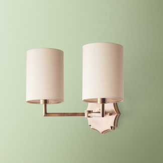 Double insignia wall fixture in antiqued brass