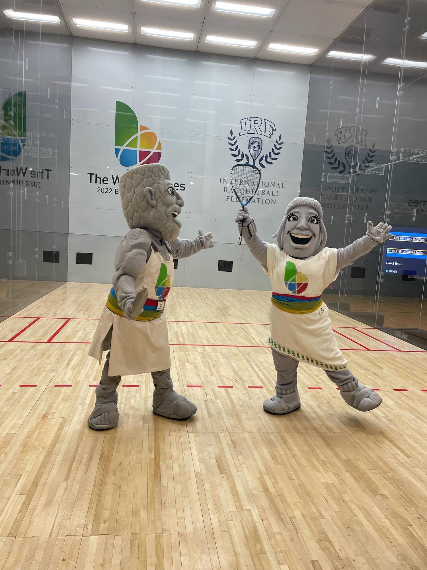 Vulcan and Vesta on the racquetball court holding a racquet.