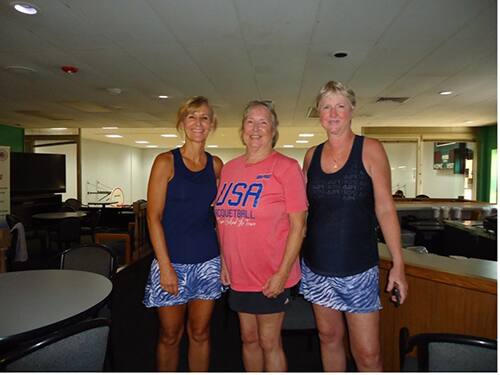 Three ladies standing in blue, red and blue shirt.
