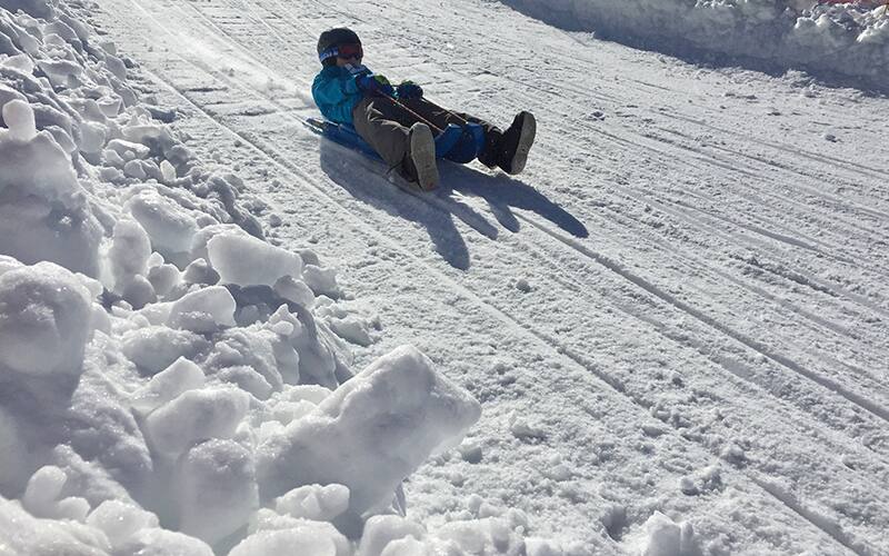 a young child riding a plastic luge sled