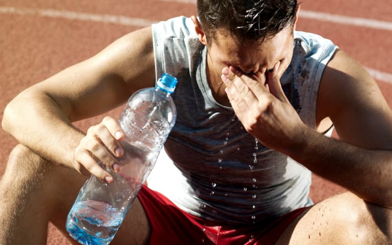 man sweating drinking water
