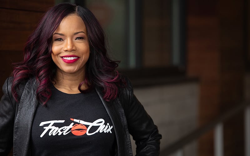 yvonne spencer is posing for a portrait photo. she is smiling and wearing a black t-shirt that reads Fast Chix.