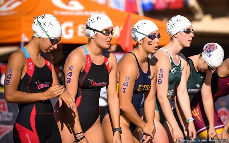 women collegiate triathletes line up on the beach before the start of the race
