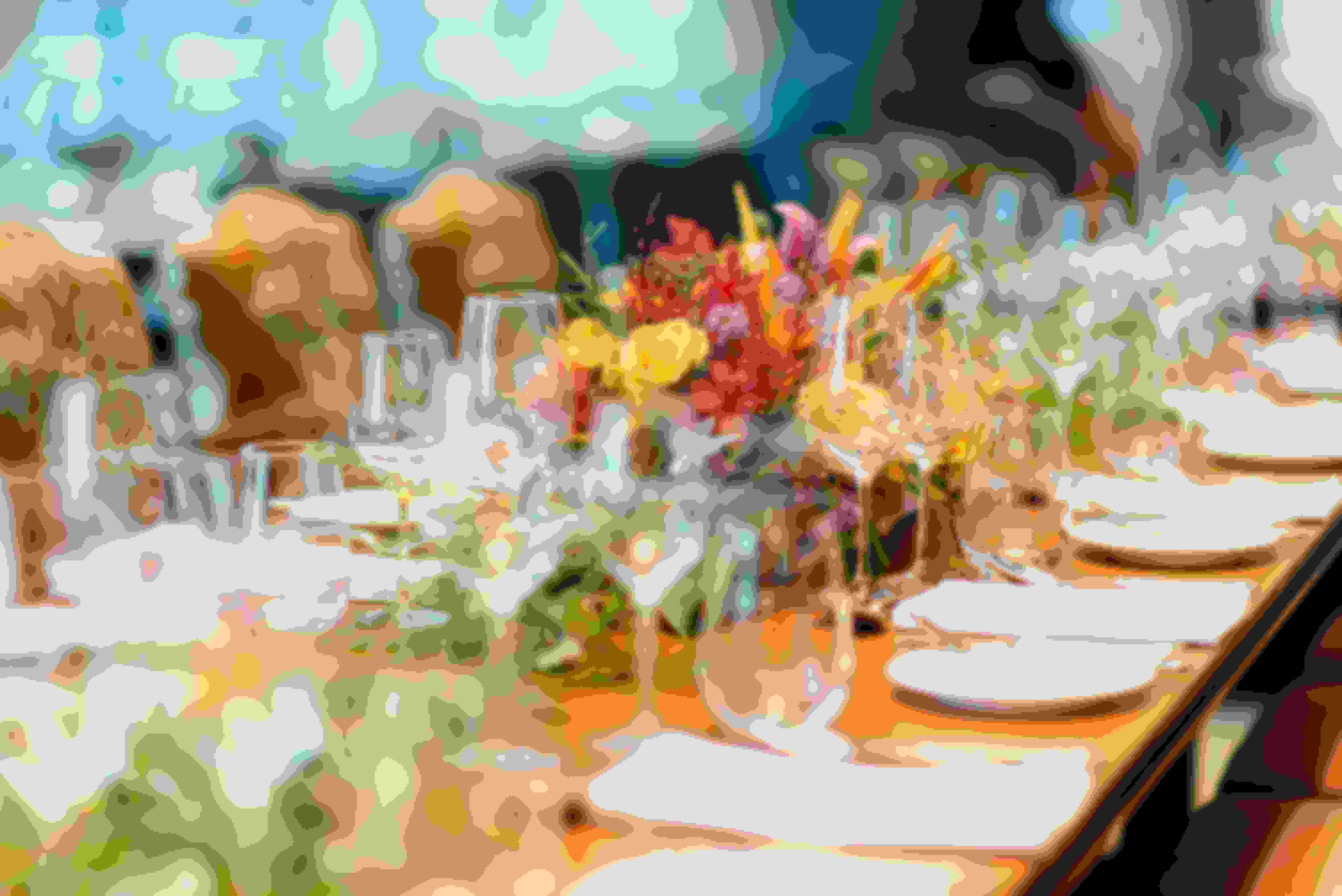 Lots of empty plates and wine glasses on a long table with a basket of flowers