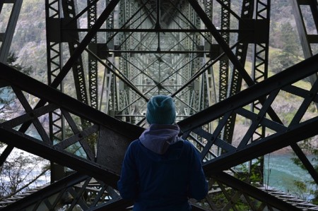 Homem contemplando engenharia de um ponte de ferro.