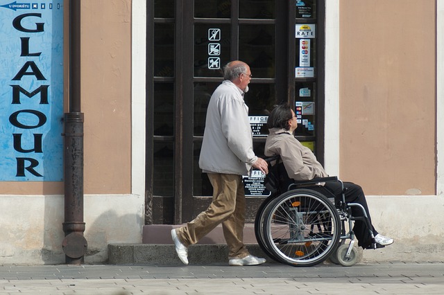 Homem guiando cadeirante na rua.