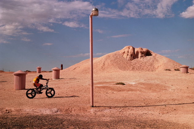 Boy on a bike. A young boy takes his bike through barren landscape in Coober Pedy. © Rae Begley.