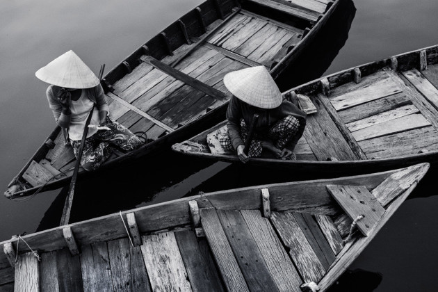 Two boat ladies in Hoi An, Vietnam. They were completely unaware of my camera. When they looked up to ask me for a boat ride, it was as simple as covering my camera in my hands and waiting for them to look away. Fujifilm X100S, fixed 35mm f/2 @ 35mm, 1/250s @ f4, 800 ISO, handheld. Monochrome conversion, curves and contrast adjustment in Adobe Photoshop CC.