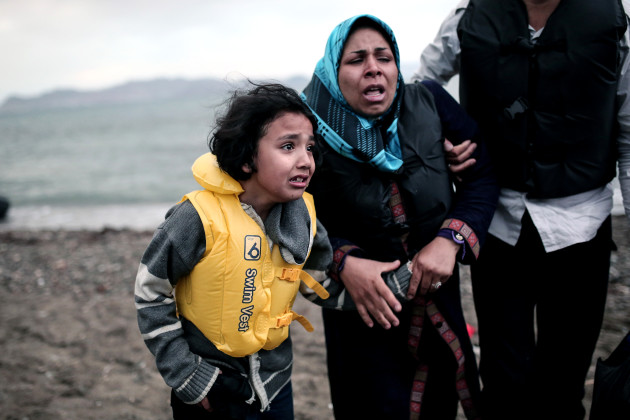 GREECE, Kos : An Afghan migrant girl holds the hand of a woman as they arrive on a beach on the Greek island of Kos, after crossing a part of the Aegean Sea between Turkey and Greece, on May 27, 2015. AFP PHOTO/Angelos Tzortzinis