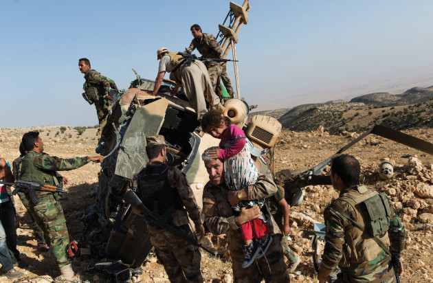 Kurdish peshmerga forces carry displaced Yazidi people from the wreckage of AN Iraqi military helicopter that delivered aid to trapped Yazidis on Sinjar Mountain. After delivering aid and picking up a number of IDPs, the helicopter crashed, wounding many and killing the pilot. Shot for The New York Times. © Adam Ferguson.