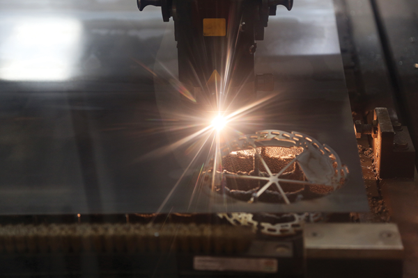 A huge sheet of steel is fed into a programed laser cutter—within seconds the discs are cut.