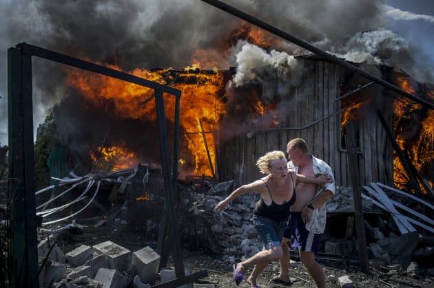 Civilians escape from a fire at a house destroyed by the air attack in the Luhanskaya village. Photo: Valery Melnikov