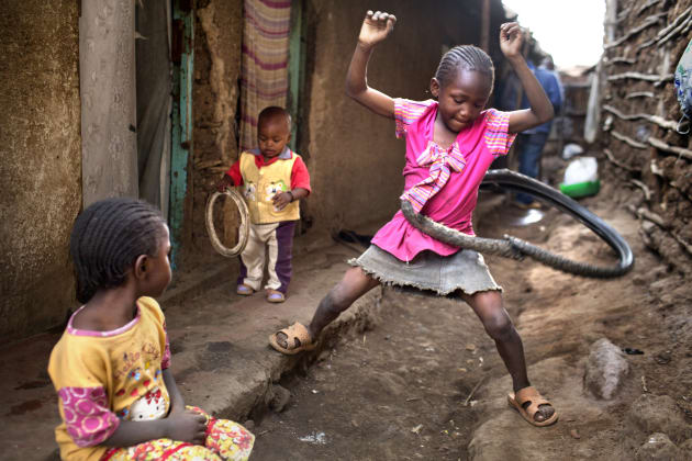 A resourceful young girl uses an old tyre as a Hula Hoop in the slum of Kibera, Kenya - the largest slum in Africa. Only 8% of girls in Kibera ever have the chance to go to school. © Deanne Fitzmaurice.