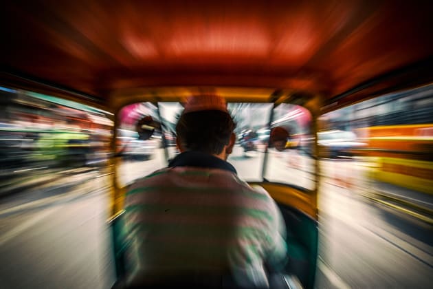 An auto rickshaw driver speeds down the street in New Delhi, India. I shot this image from the backseat with a slow shutter to achieve the zoomed effect for a sense of motion. Canon EOS 6D, 16-35mm f/2.8 lens @ 16mm, 1/40s @ f14, ISO 160, handheld. Contrast, curves and levels adjustment, sharpening in Photoshop CC. Photo © Drew Hopper.