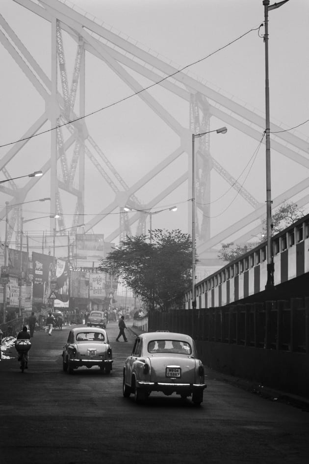 Cold and misty morning by Howrah Bridge in Kolkata, India. The old Classic Ambassadors in black and white really capture the essence of India, in an almost timeless manner. It could have been taken in any era. Canon 6D, Canon 24-105mm f/4 lens @ 88mm. 1/200s @ f4.5, ISO 400, handheld.