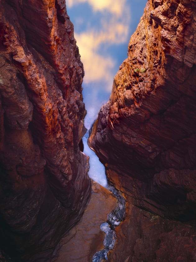 Looking 100 metres down into the gorges of Karijini National Park makes you feel so small. The warm sunrise light on the clouds above is reflected in the water below. I like the way it feels like you are looking up and out of the gorge. 
Sony A7r, Sony 70-200mm f/4 @ 129mm, 2s @ f11, ISO 100