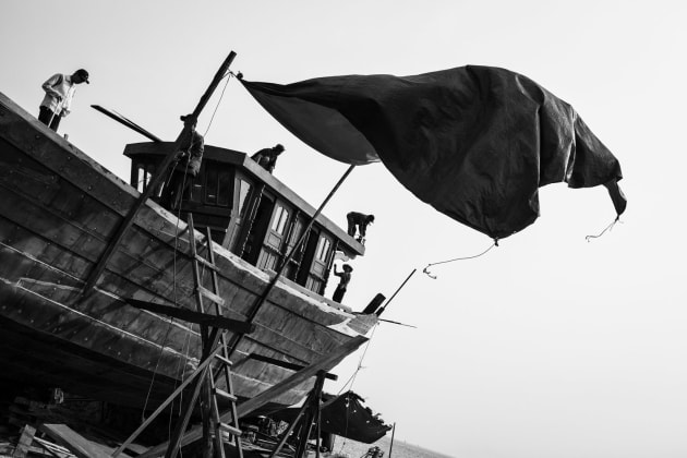 Men building a wooden ship in Central Vietnam. The wind was howling so I wanted to capture a sense of setting sail with the sail flapping in the wind. The sky was overcast so I converted to black and white, which helped draw the focus to the men working.
Fujfilm X100S, fixed 35mm f2 @ 35mm @ f/5.6, 400 ISO. Monochrome conversion, contrast and levels adjusted in Adobe Lightroom.