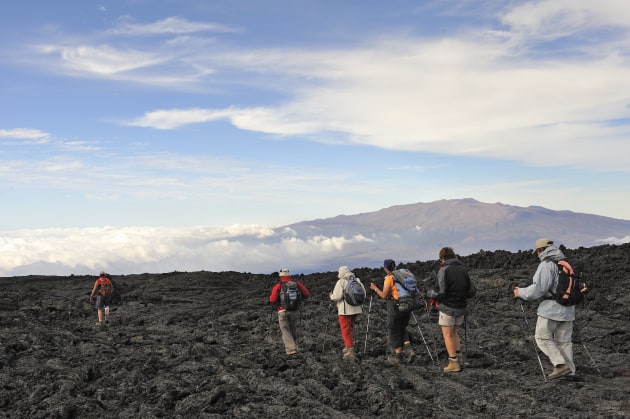 Hikers walk on cooled lava, Hawaii, Big Island. (Stock image, Getty Images.)