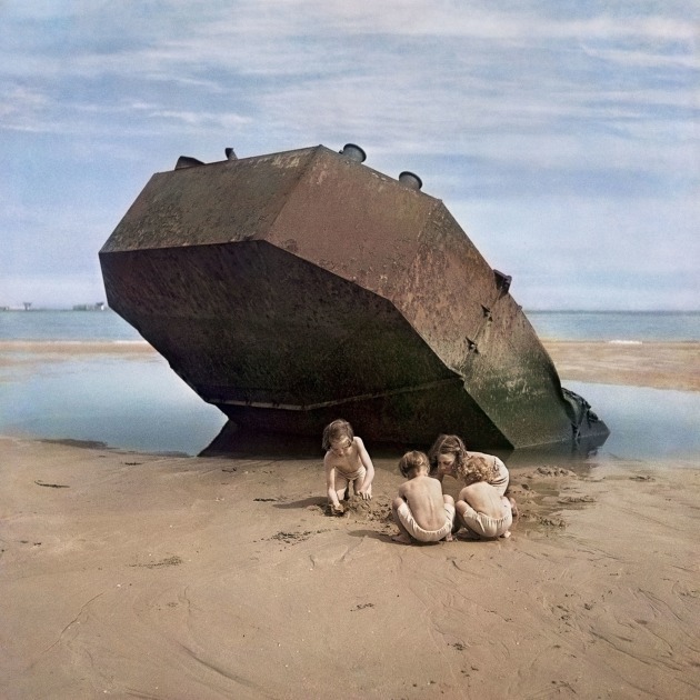 Children play among the wreckage of the D Day invasion. Normandy, France, 1947. © David Seymour / Magnum Photos. 
“David ‘Chim’ Seymour returned to Europe on an assignment for 'This Week' magazine in April 1947. He travelled to the Normandy beaches in order to revisit the location where the Allied D-Day invasion took place on June 6, 1944. Chim’s particular interest in how the young dealt with and reacted to years of conflict led him to these kids playing happily on the beach near the ominous steel shell of an abandoned fortification.
The four children seem deeply engrossed in their imaginative plan to make a sand castle or some other creation, somehow ignoring what is hanging over their heads. The terror of D-Day lingers over this image of children and calm weather, with clouds softening the sunshine.