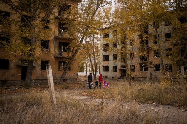 A family passes derelict housing blocks in the town of Kurchatov, © Phil Hatcher-Moore. Kazakhstan. Kurchatov was the headquarters of the Soviet nuclear project in Kazakhstan during the Cold War, and a quarter of the world’s nuclear tests were conducted in the Semipalatinsk Test Site, just south of the town.