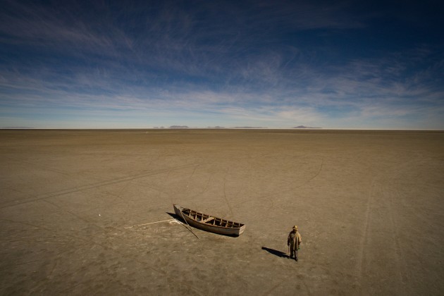 © Josh Haner/The New York Times. Felix Condori, 31, the mayor of Llapallapani, next to a boat in the dry bed that was once Bolivia's second-largest lake shown on May 1, 2016. Mr Condori, a former fisherman, now must travel to find construction jobs as a means to make money now that the lake that defined their culture and livelihood disappeared.