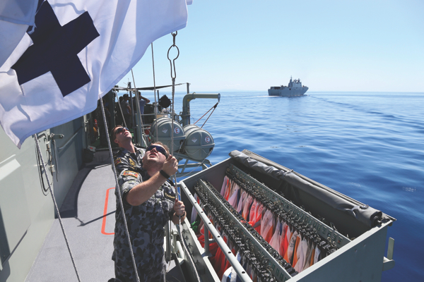 Signalmen on HMAS Stuart communicate via flag during Officer of the watch manouevres with HMAS Canberra. Credit: Defence