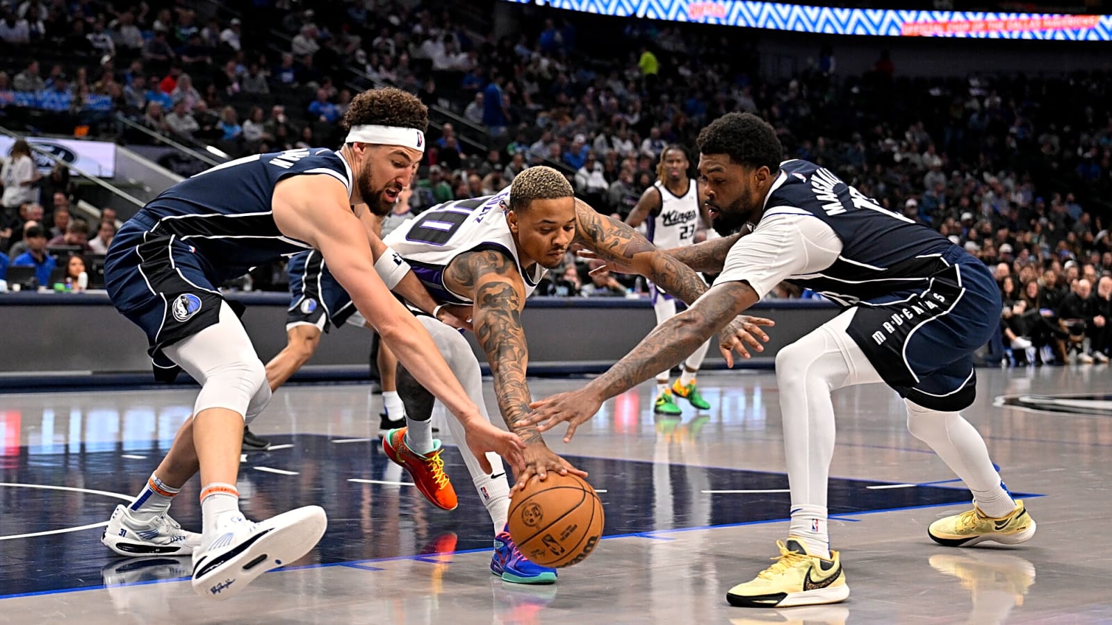 Klay Thompson, Naji Marshall, and Markelle Fultz battle for a loose ball in Dallas during a regular season Mavericks vs. Kings 2025 matchup