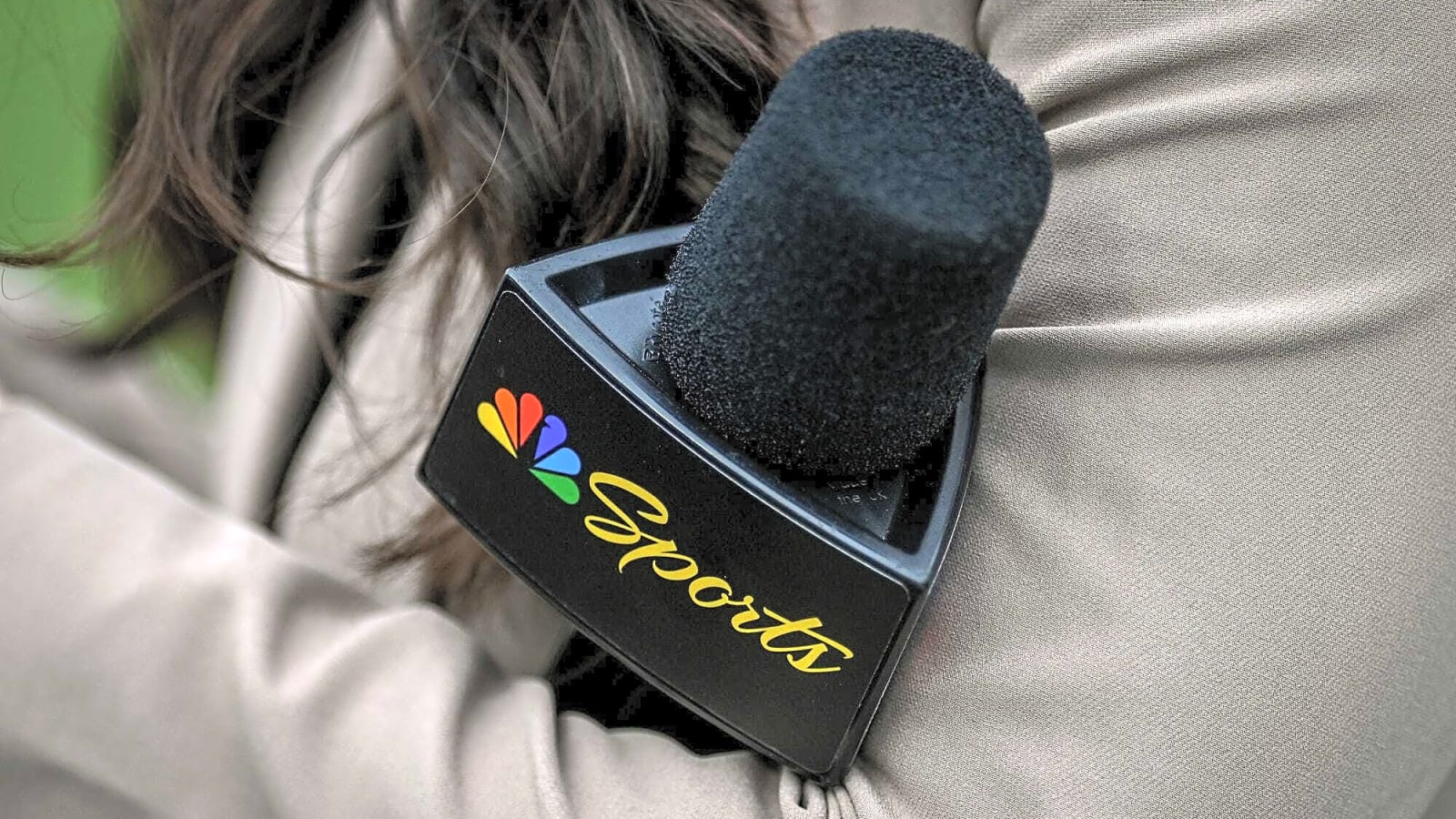 reporter on football sideline holds a microphone with the NBC Peacock