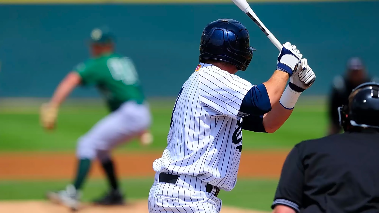 A baseball player at bat getting ready to receive an incoming pitch from a pitcher on the mound