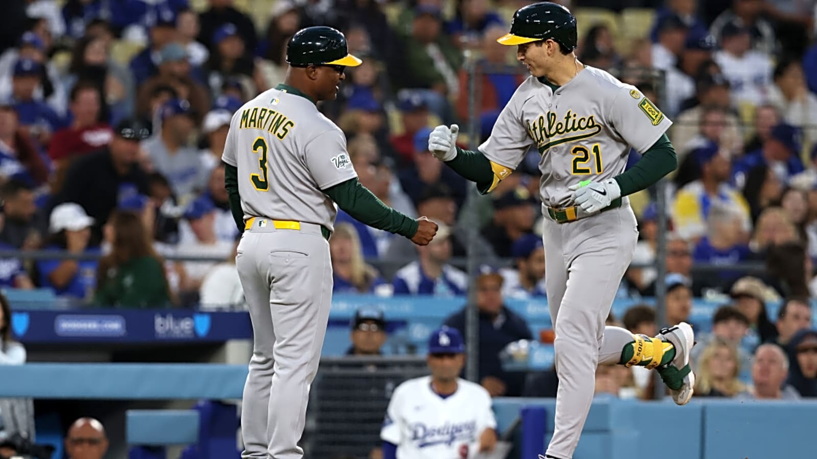 Athletics first base Tyler Soderstrom (21) reacts with third base coach Eric Martins (3) after hitting a home run at Dodger Stadium.