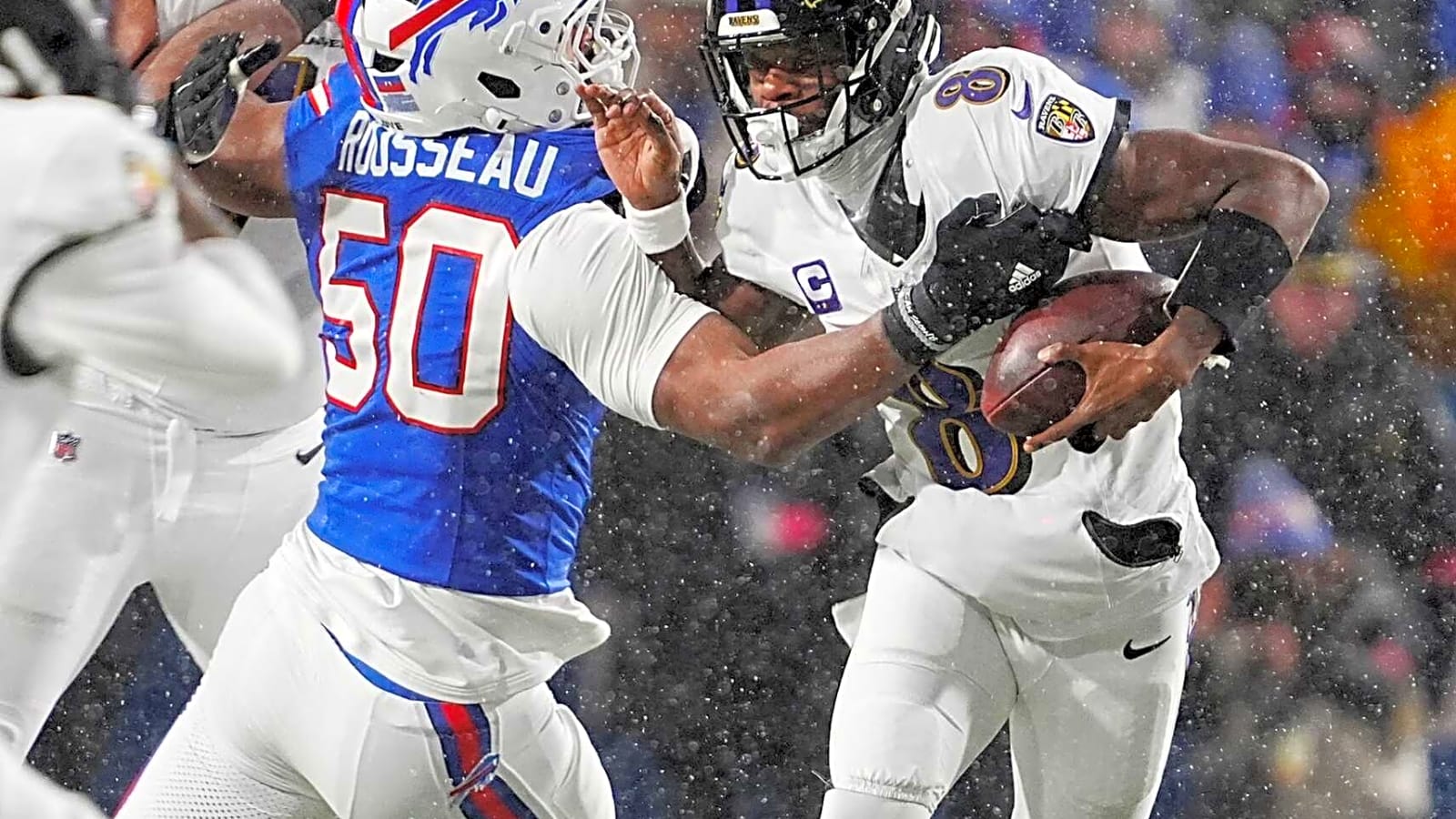 Baltimore Ravens quarterback Lamar Jackson (8) is breaking away from a tackle by Buffalo Bills defensive end Greg Rousseau (50) in Highmark Stadium.
