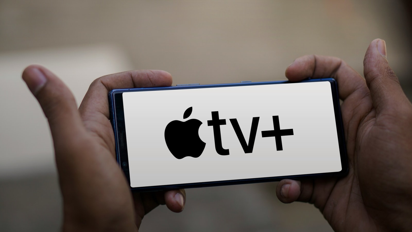 Apple TV+ logo on a cell phone held sideways in a person's hands