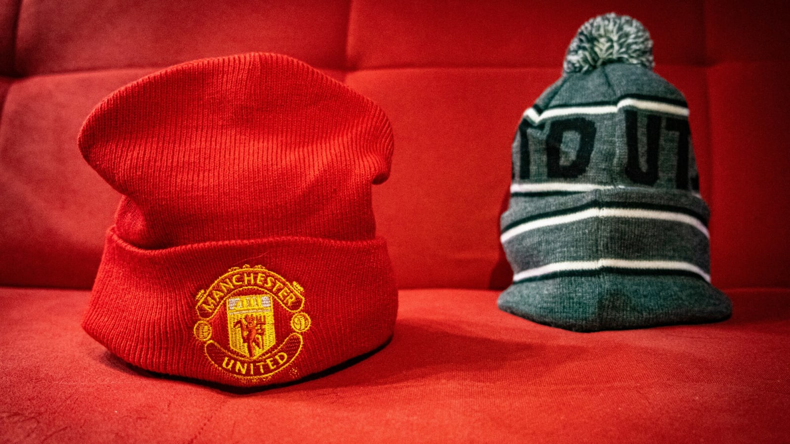 Red Manchester United hat on a red seat with gray hat behind