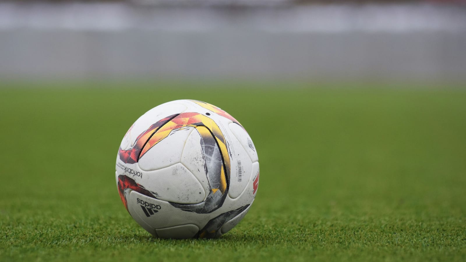 white adidas soccer ball sitting on a green field during the day